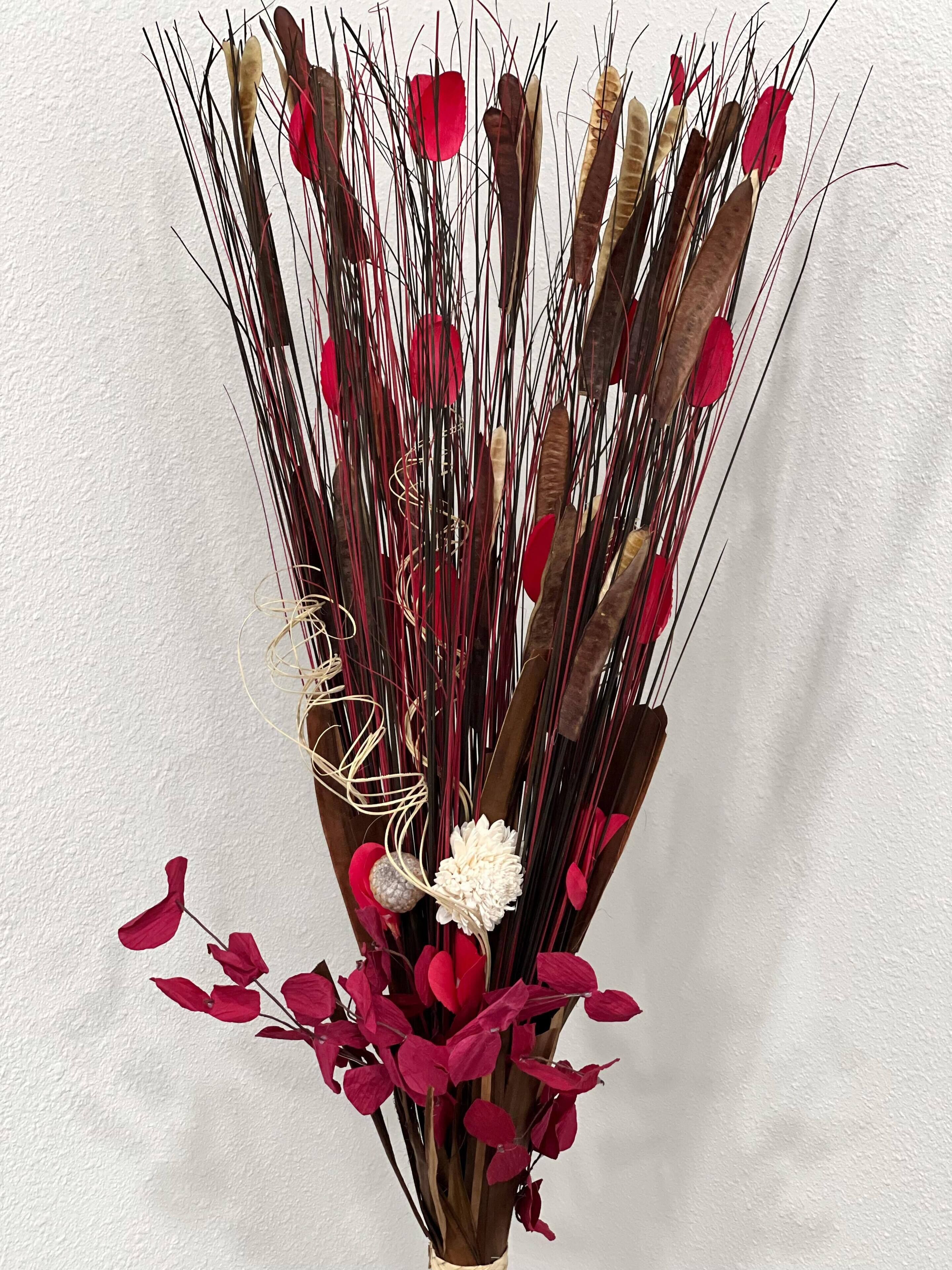 A bouquet of dried plants and flowers in a brown vase.