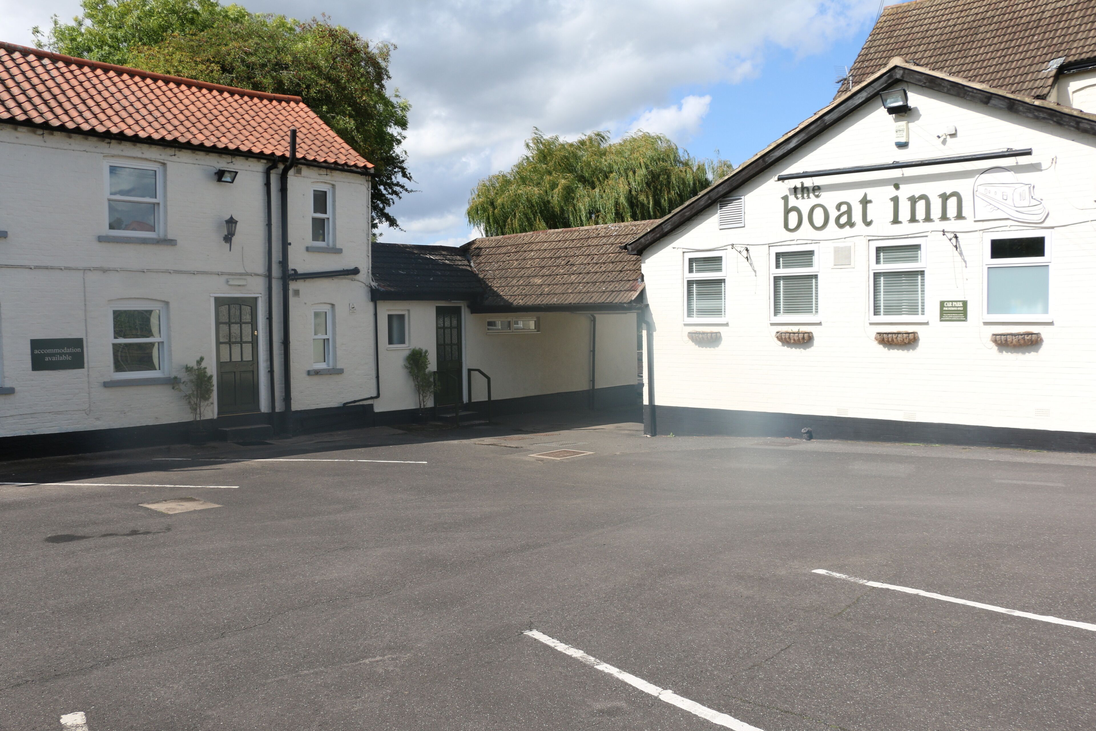 A building with a sign reading "the boat inn" and a parking lot in front.