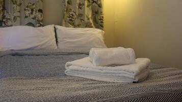 Una cama bien hecha con una colcha estampada y una toalla blanca doblada encima.