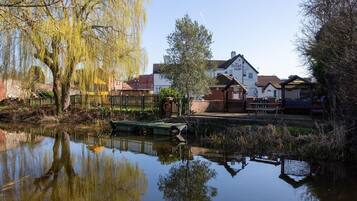 Escena junto al río con una barca amarrada cerca de un edificio blanco con un letrero que dice "The Boat Inn".
