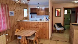 Un intérieur en bois comprenant une table et des chaises, un coin cuisine et un petit espace salon.