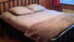 Un lit avec une tête de lit, une couverture et des oreillers.