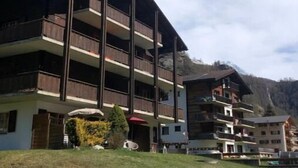 Un hôtel à plusieurs étages, doté de balcons, situé dans un cadre montagneux.