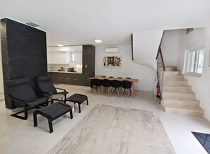 Un salon moderne comprenant un canapé, une table basse et un coin repas avec des chaises et une table.