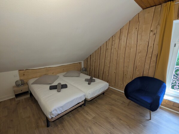A bedroom with two beds, wooden walls, a chair, and a window. - LE MILAN ROYAL APARTMENT IN A CHARACTERFUL ESTATE (Montperreux)
