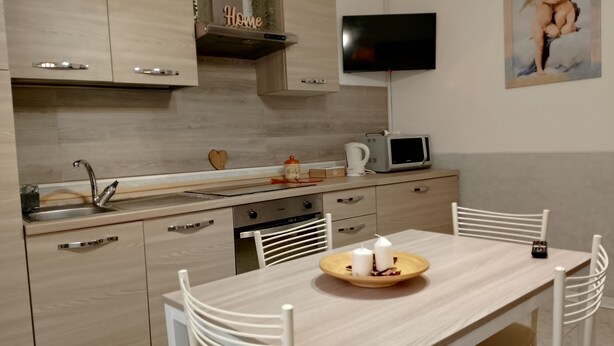 Een moderne keuken met een ingebouwde magnetron, een spoelbak en een eettafel met stoelen.