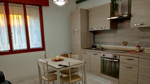 Een moderne keuken met houten kasten, een ingebouwde oven en een eethoek met een tafel en stoelen.