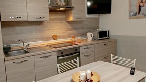 Een moderne keuken met houten kastjes, een ingebouwde oven, een magnetron en een eettafel met een dienblad kaarsen.