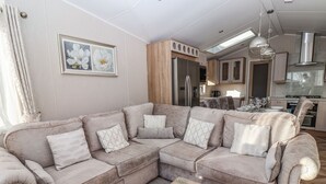 A modern living room with a sectional sofa, a wooden coffee table, and a kitchen in the background. - Owls Nest (York)