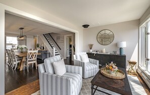 Un salón amplio con sillones a rayas, una mesa de centro de madera y un comedor con mesa y sillas de madera.