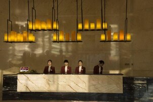 A reception desk with a marble top and four staff members seated behind it.