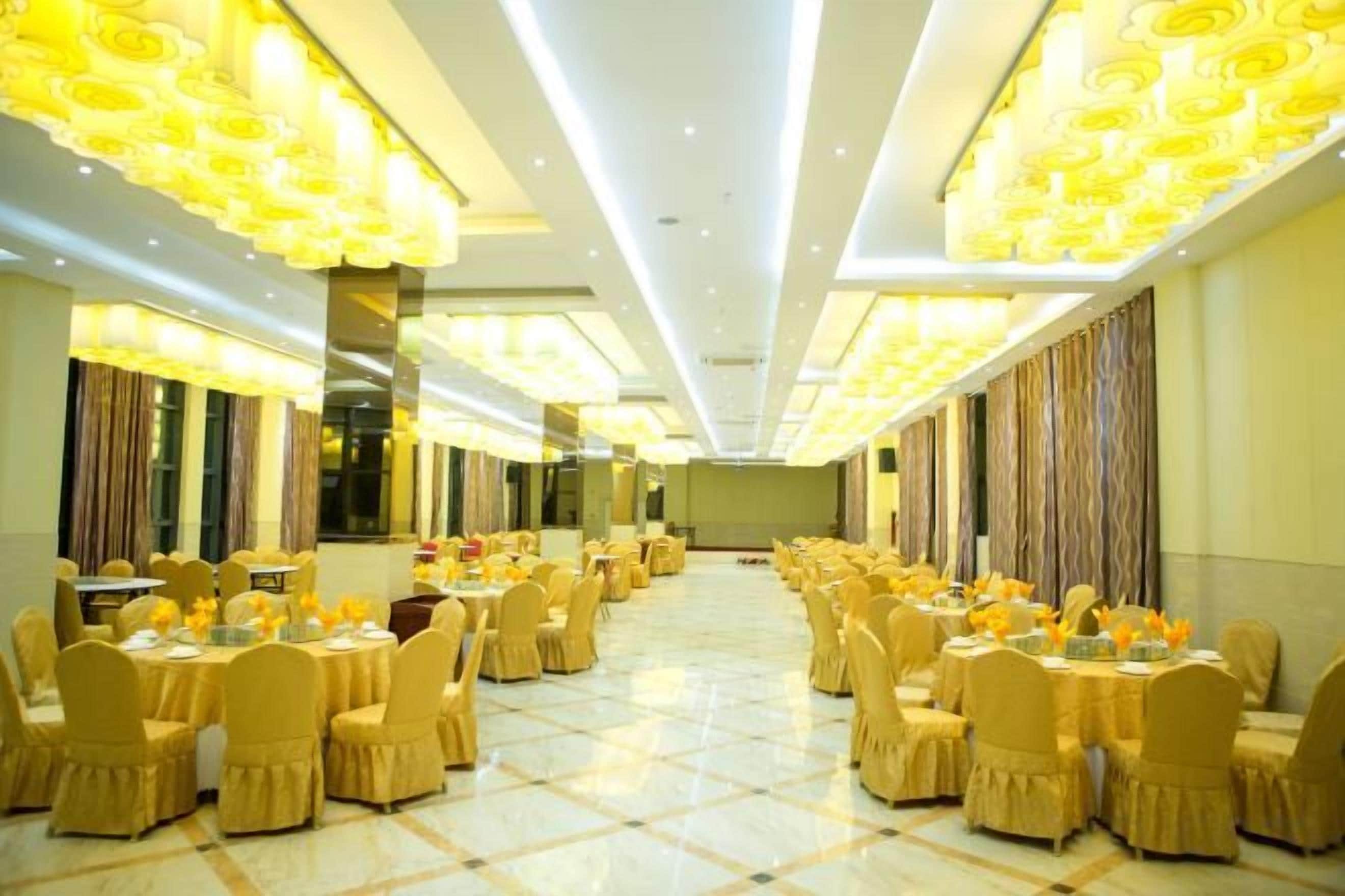 A banquet hall with round tables and chairs, a high ceiling, and a polished floor.
