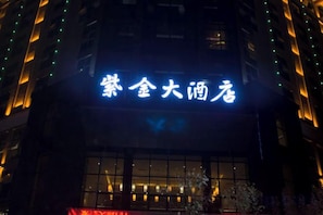 A building with illuminated signage in a foreign script, large windows, and a visible entrance. - Zijin Hotel (Jiange)