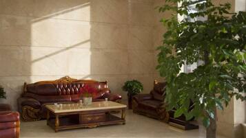 A lobby with a leather sofa, a coffee table, and a potted plant.