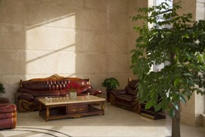 A lobby with a leather sofa, a coffee table, and a potted plant. - Zijin Hotel (Jiange)