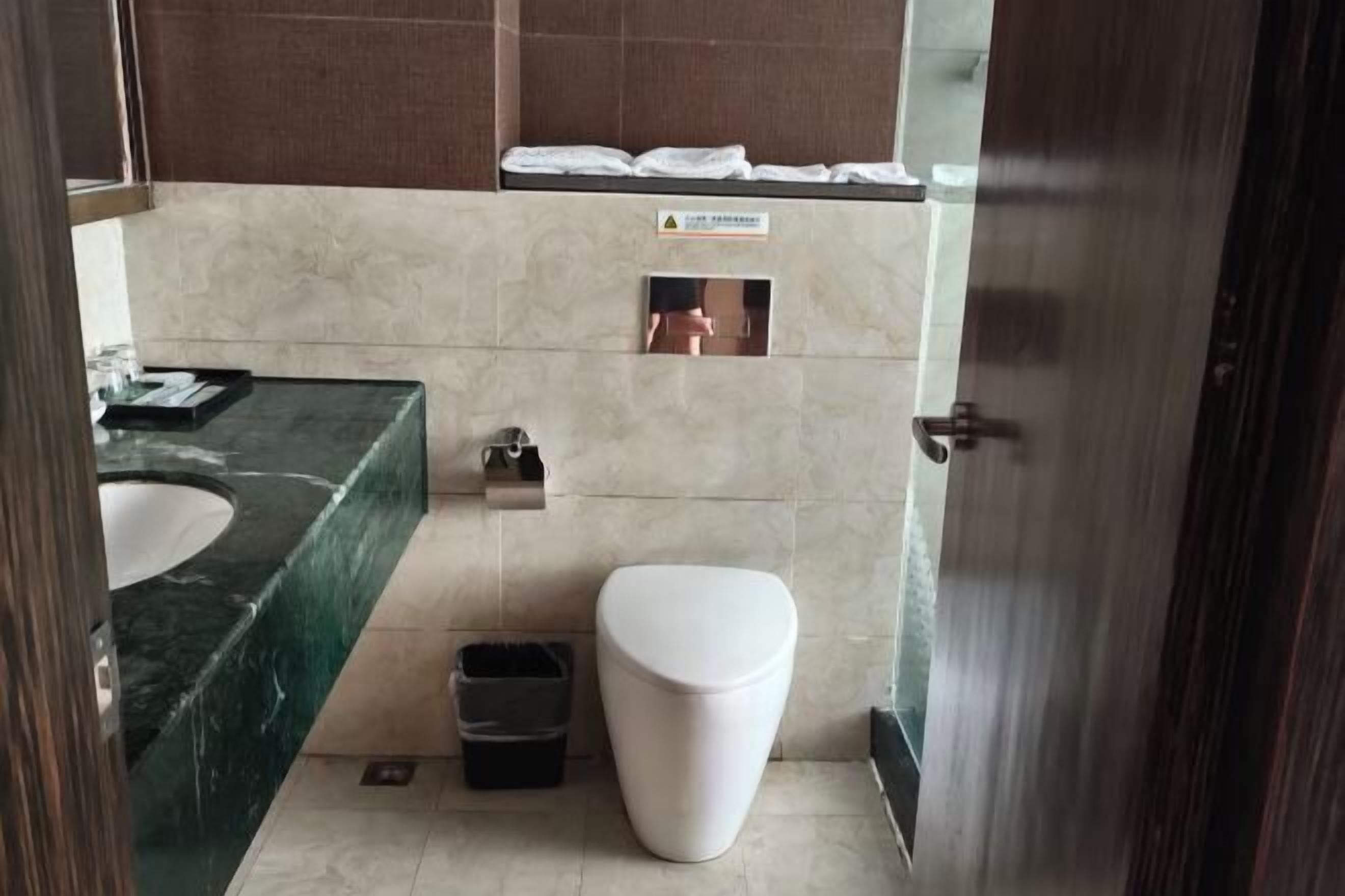 A bathroom with a marble sink, a toilet, and a trash bin.