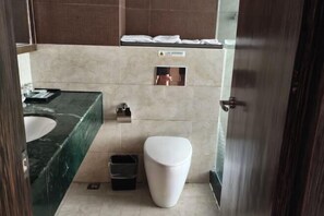 A bathroom with a marble sink, a toilet, and a trash bin.