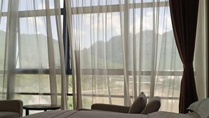 Habitación de hotel con un ventanal grande, una cama, una silla y una mesita.