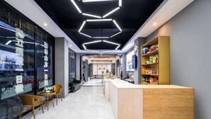 A modern interior with a reception desk, seating area, and a wall with glass panels. - Yebang Convenience Hotel (Guilin North Railway Station) (Lingchuan)