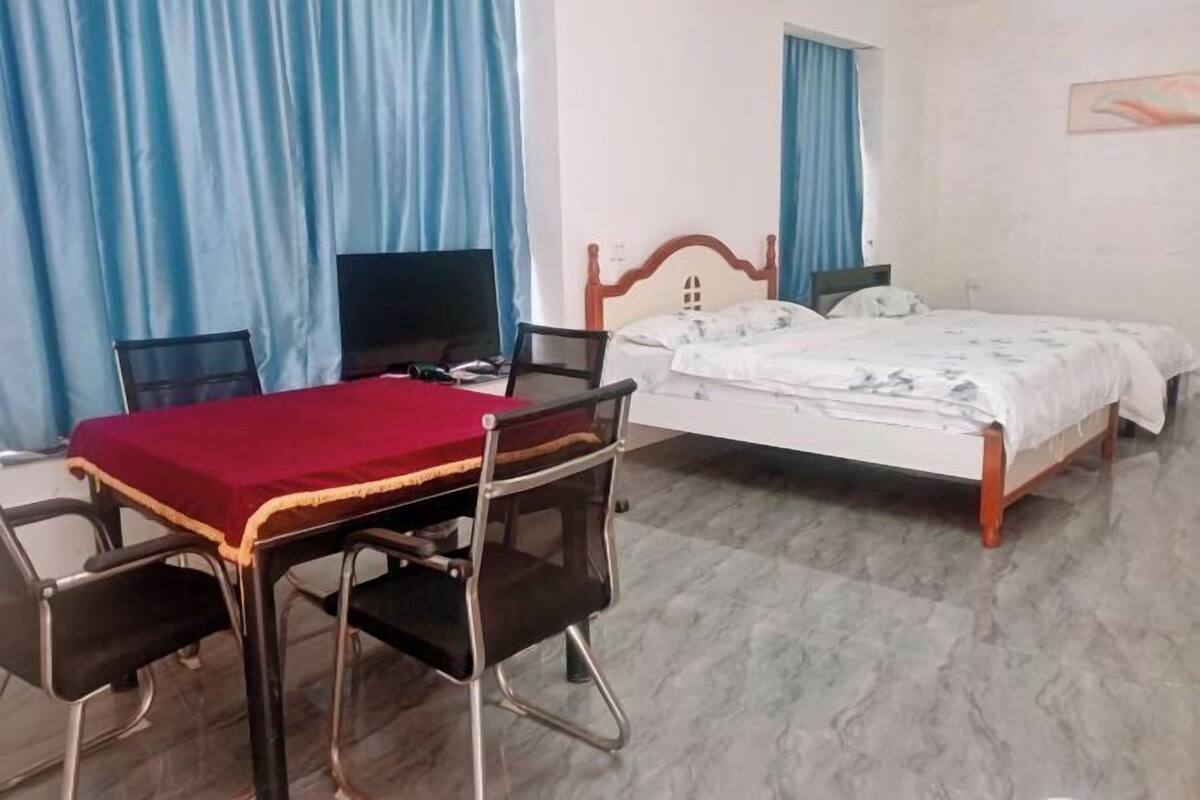 A hotel room with a bed, a desk with a chair, a television, and curtains.