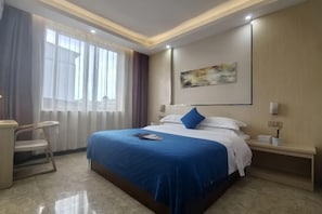 A hotel room with a bed, a desk, and a chair.