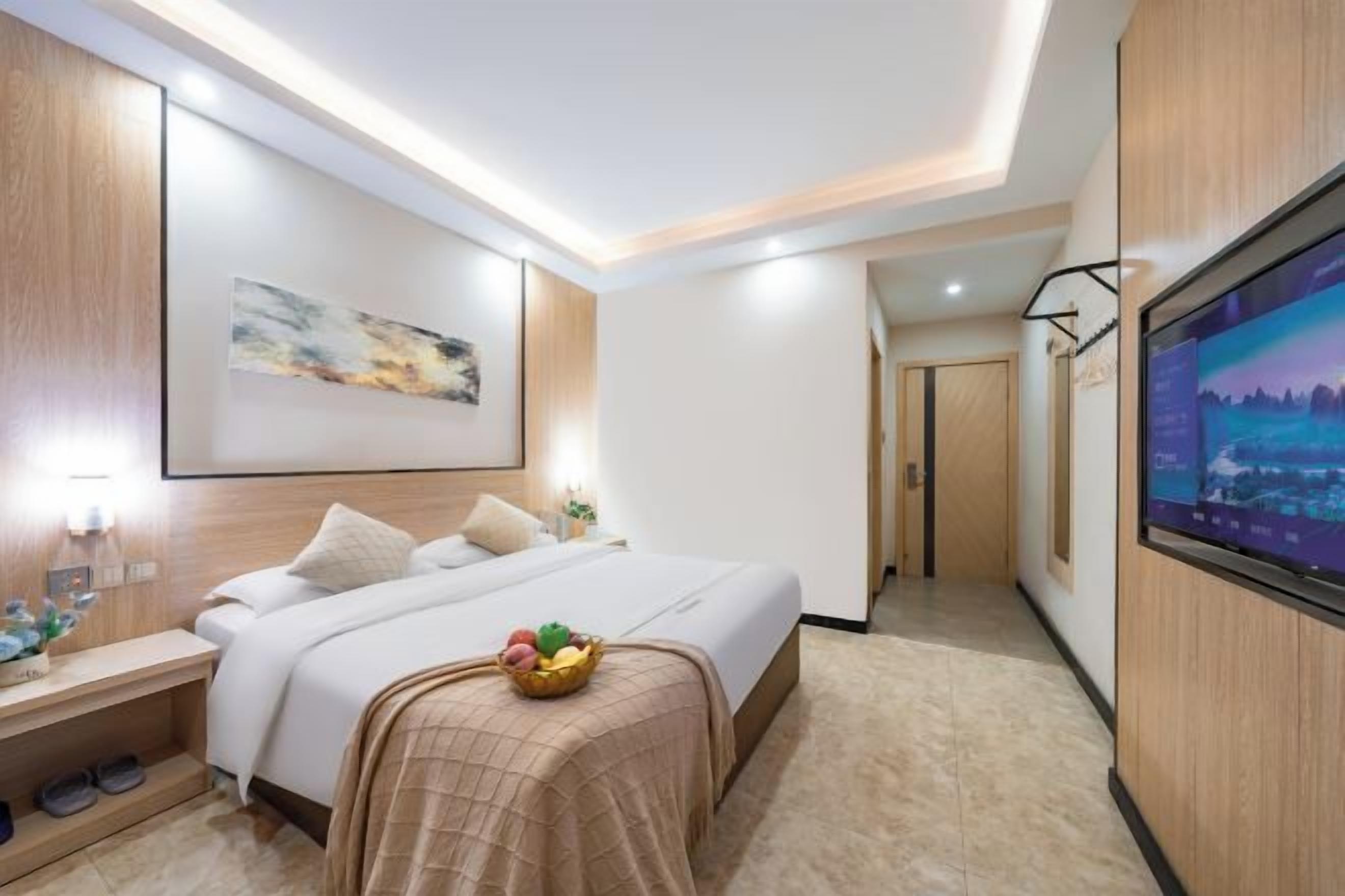 Una habitación de hotel con cama, mesita de noche, televisor y una obra de arte en la pared.