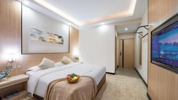 Una habitación de hotel con cama, mesita de noche, televisor y una obra de arte en la pared.