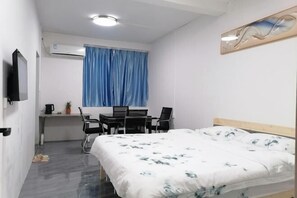 Ein Hotelzimmer mit einem Bett, einem Schreibtisch mit Stuhl, einem Fernseher und einer Klimaanlage.