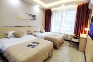 Ein Hotelzimmer mit zwei Betten, einem Schreibtisch, einem Stuhl, einem Fernseher und einem Fenster mit Vorhängen.