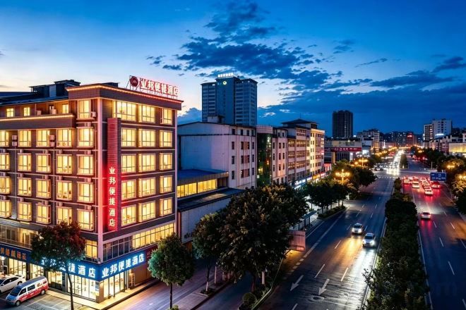 A multi-story hotel with a prominent sign, located in an urban setting with a busy street in the background.