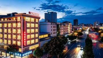 A multi-story hotel with a prominent sign, located in an urban setting with a busy street in the background.
