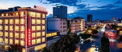 A multi-story hotel with a prominent sign, located in an urban setting with a busy street in the background.