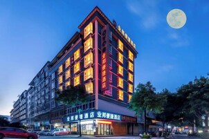 Un hotel de varios pisos con señalización iluminada y una luna grande en el cielo.