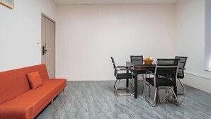 A room with a sofa, dining table, chairs, and a door. - Yebang Convenience Hotel (Guilin North Railway Station) (Lingchuan)