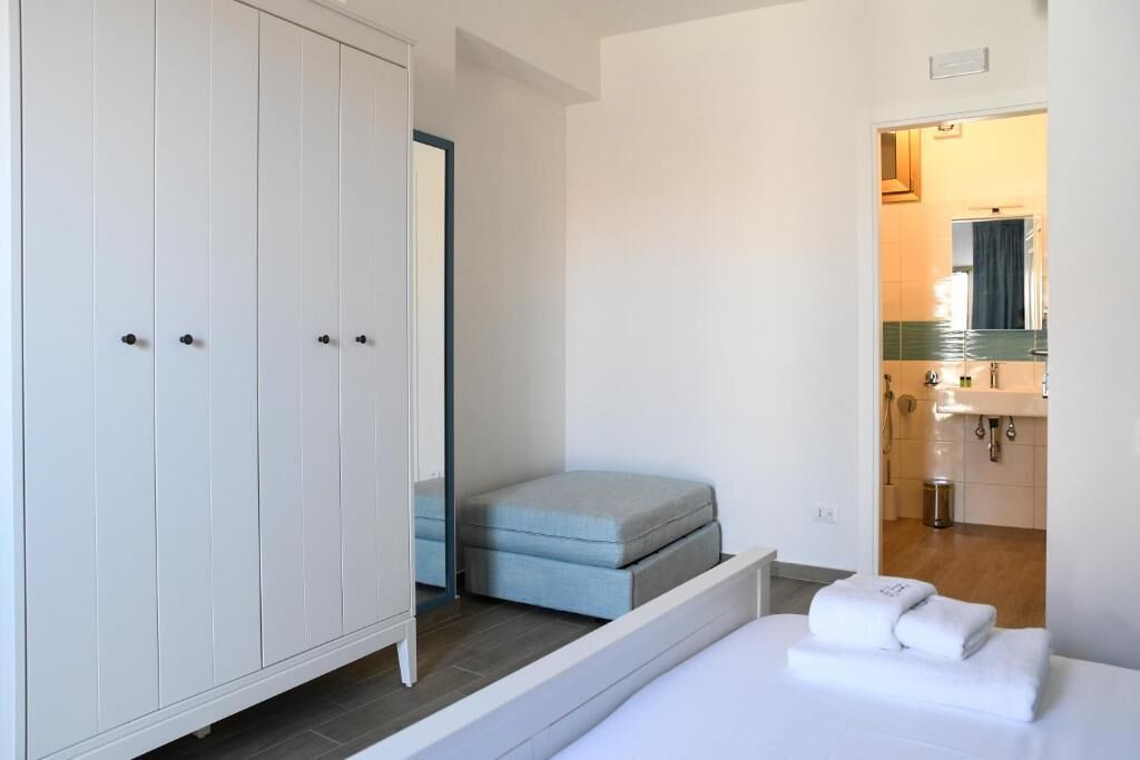 A bedroom with a bed, a wardrobe, and a bathroom visible through an open door.