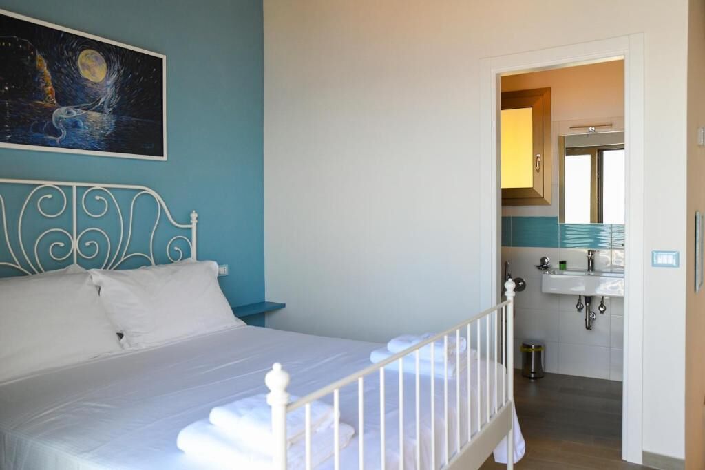 Une chambre à coucher avec un lit, un tableau au mur et une vue sur la salle de bain.
