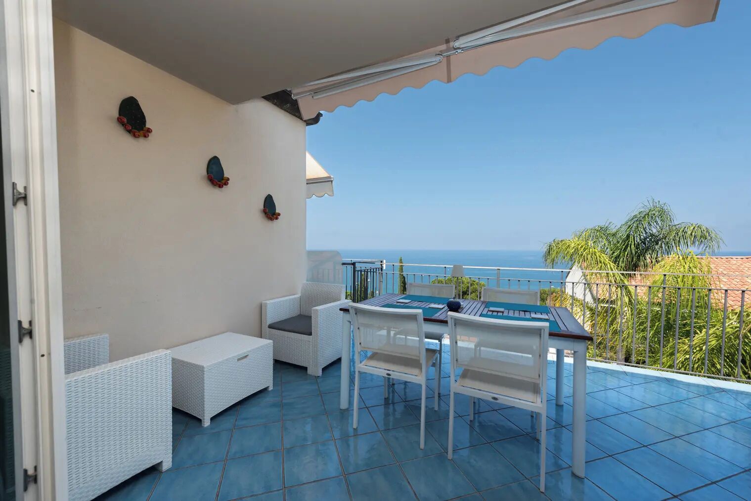 Un balcon avec une table et des chaises, un canapé blanc et une vue sur la mer.