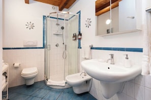A bathroom with a glass-enclosed shower, a toilet, a bidet, and a sink with a mirror above. - Luxury sea View, With Infinity Pool in Sicily (Cefalù)