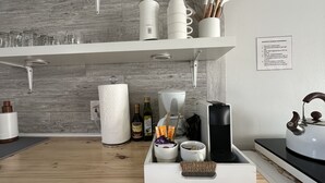 Une cuisine moderne avec des meubles blancs, un plan de travail en bois et divers appareils de cuisine.