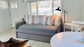 Un salon moderne avec un canapé gris, une table ronde blanche et une grande sculpture en bois.