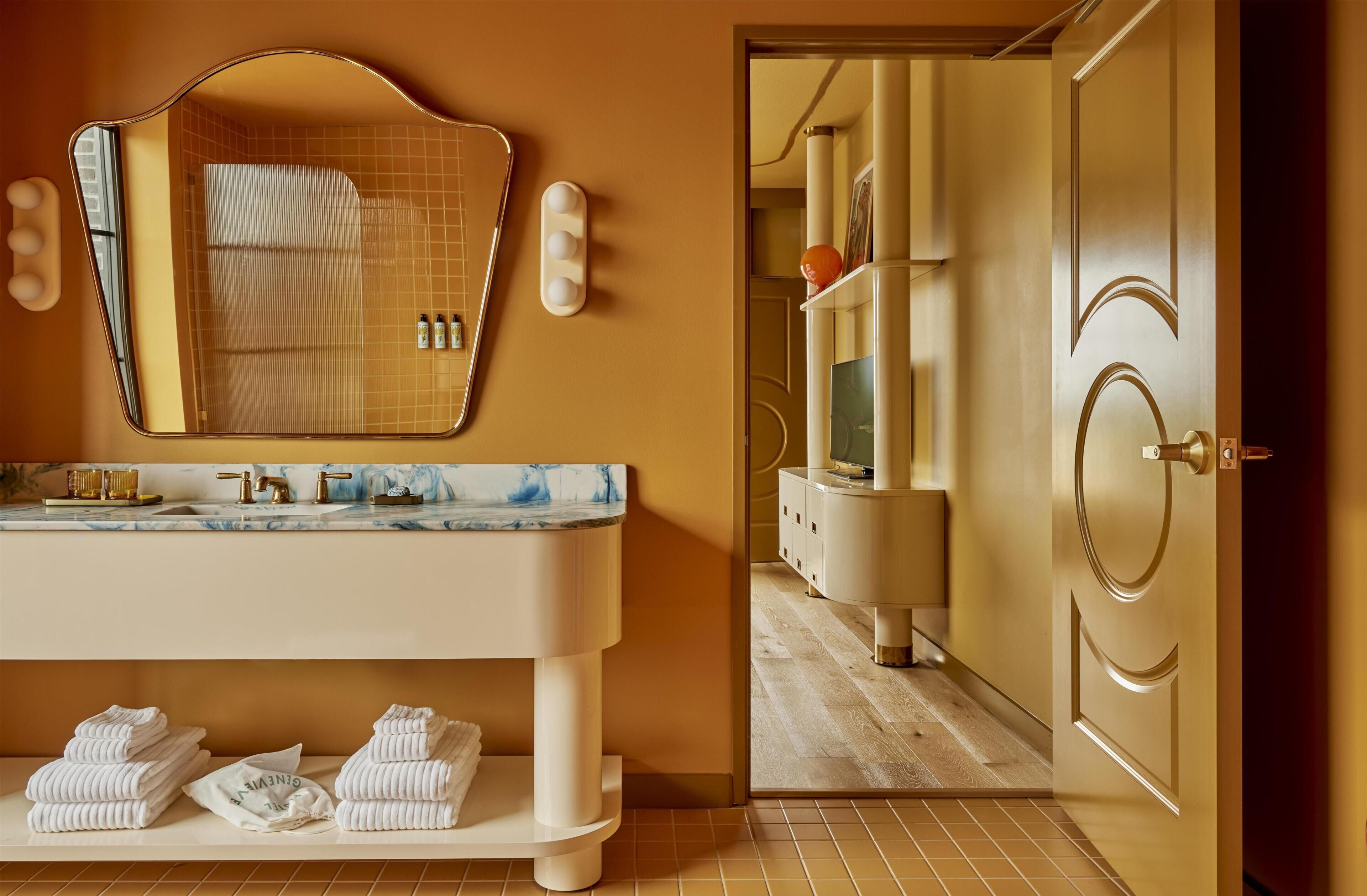 A bathroom with a marble countertop, a sink, a mirror, and a towel rack with folded towels.