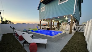 A pool area with lounge chairs, a small inflatable pool, and a covered seating area with string lights. - Reel Paradise: NEW Luxury 5BR! Private POOL + FirePit & OutdoorTV. Great Views! (Port Aransas)