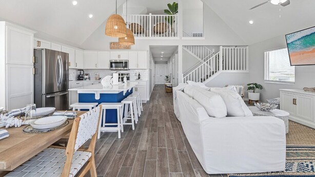 A modern kitchen with white cabinets, a stainless steel refrigerator, and a blue island. - Reel Paradise: NEW Luxury 5BR! Private POOL + FirePit & OutdoorTV. Great Views! (Port Aransas)