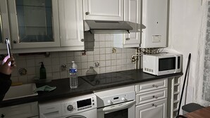 Cozinha compacta com armários brancos, micro-ondas, máquina de lavar e pia.
