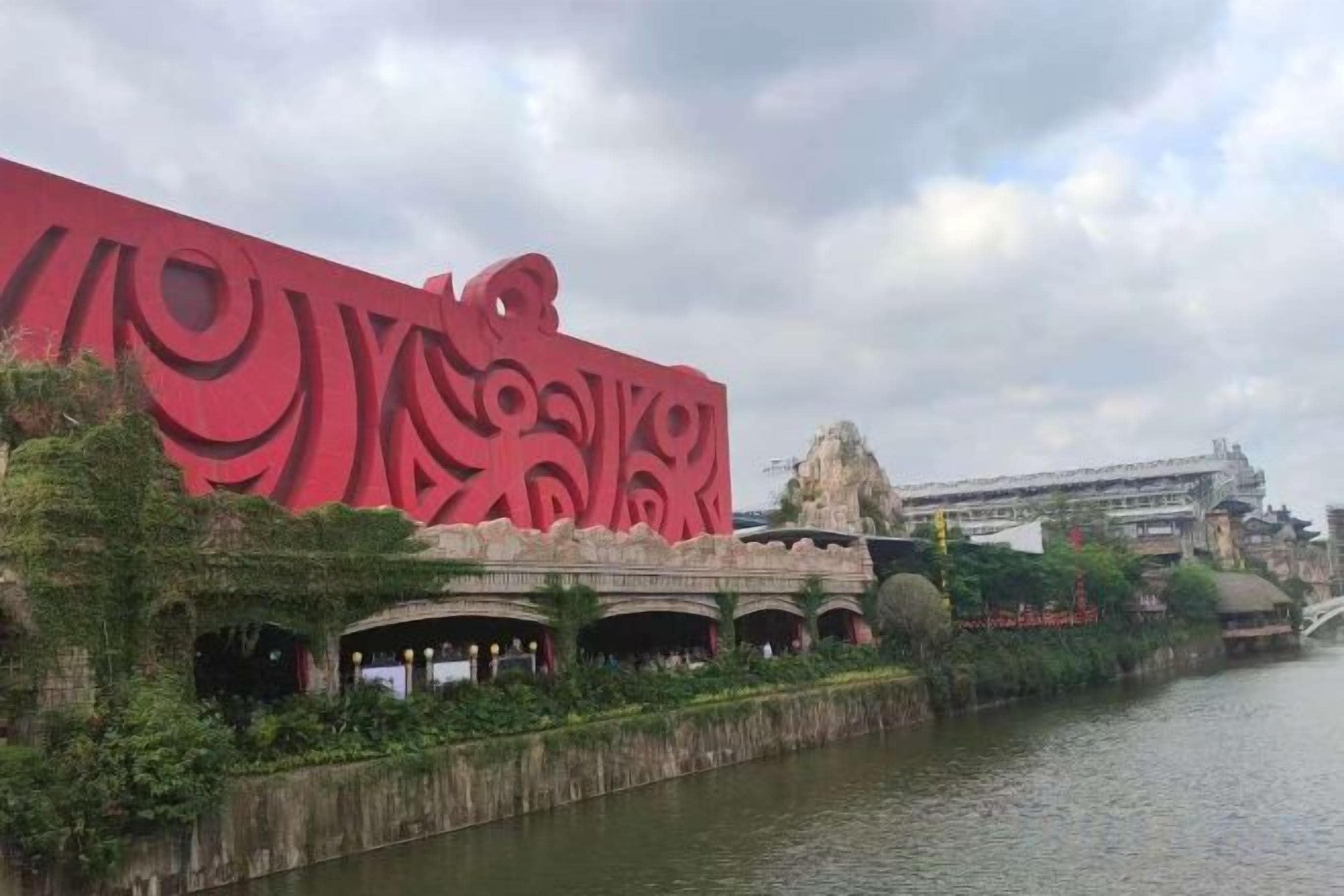 A building with a distinctive red facade and a river in the foreground.