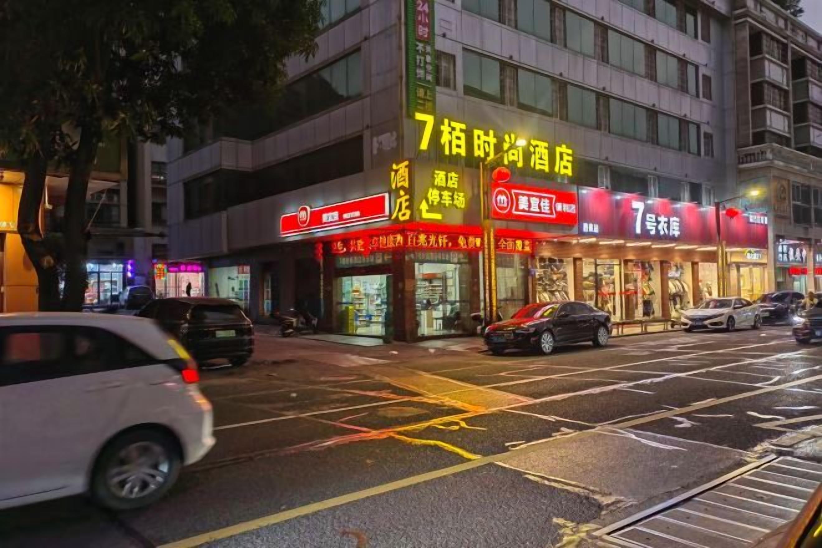 A building with multiple storefronts, including a brightly lit establishment with a sign in a foreign language.