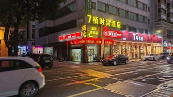 A building with multiple storefronts, including a brightly lit establishment with a sign in a foreign language.