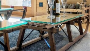 Un interior de madera con una mesa de vidrio, una botella de vino y copas.