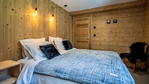 Un dormitorio con paneles de madera, una cama, mesitas de noche y una silla.