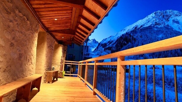 Un balcón de madera con vistas a montañas nevadas.